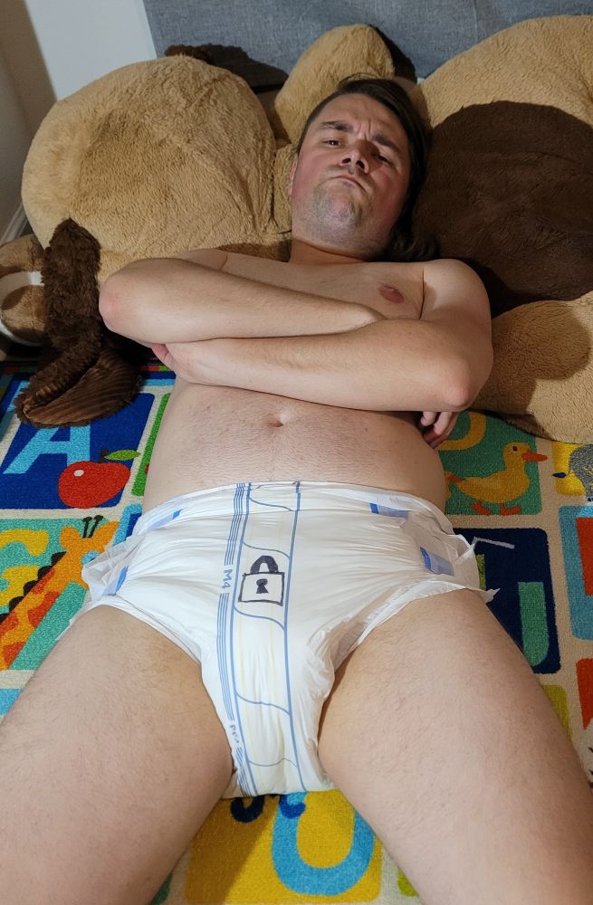 An angry Blankey lays with his arms crossed frowning at the camera wearing nothing but a diaper with a lock drawn on the front