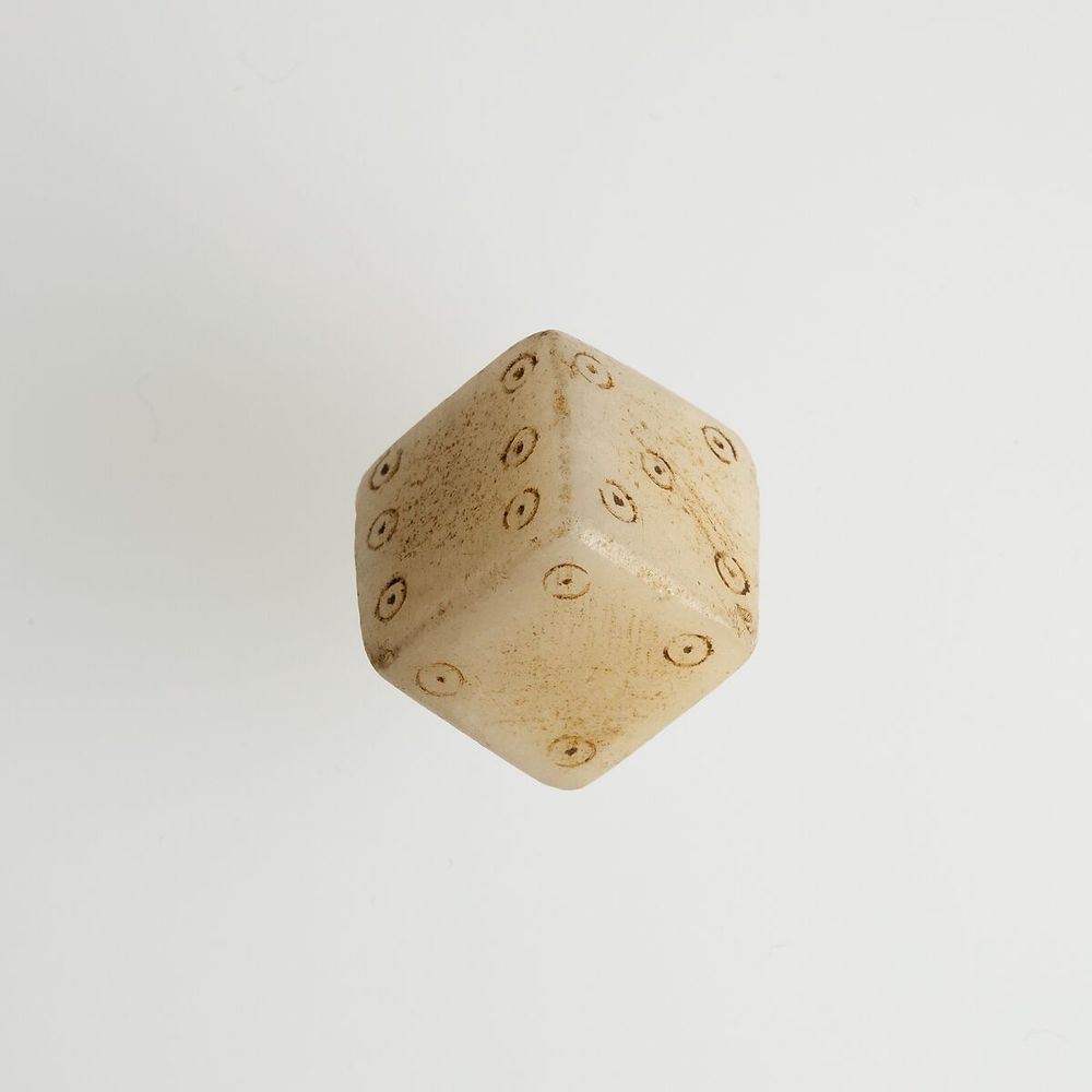 An ancient roman die made of white stone showing six, five, and four pips -- reflecting the standard pip placement still in use today. https://www.metmuseum.org/art/collection/search/551069