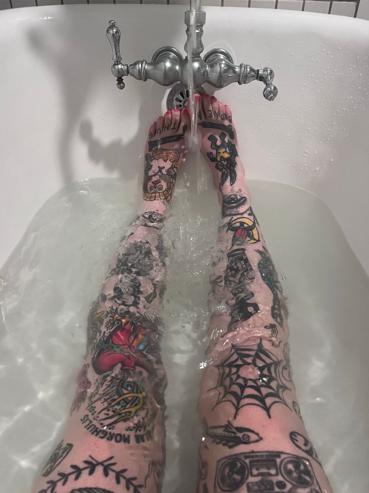 My tattooed legs in a bathtub - my toes say bone thug 🤗