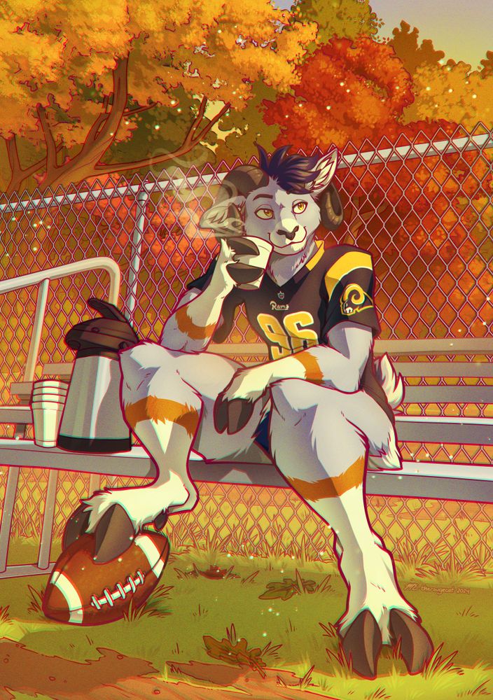 A grey anthropomorphic ram wearing a Rams jersey. He is sitting on a bench outside and drinking something warm from a styrofoam cup. The trees behind him are brightly autumnal.