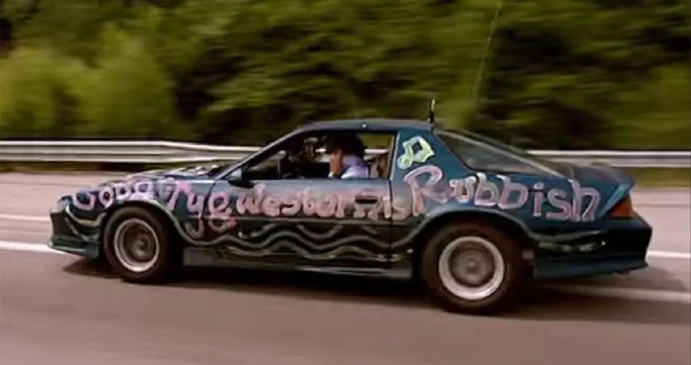 A dark blue 1989 Camaro. The side has been painted in pink with the words "country and western music is rubbish"