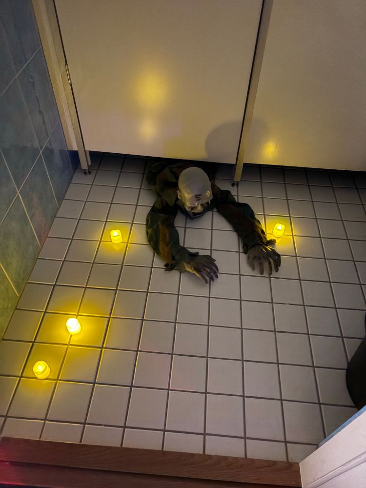 A man being pulled under a door, surrounded by candles 