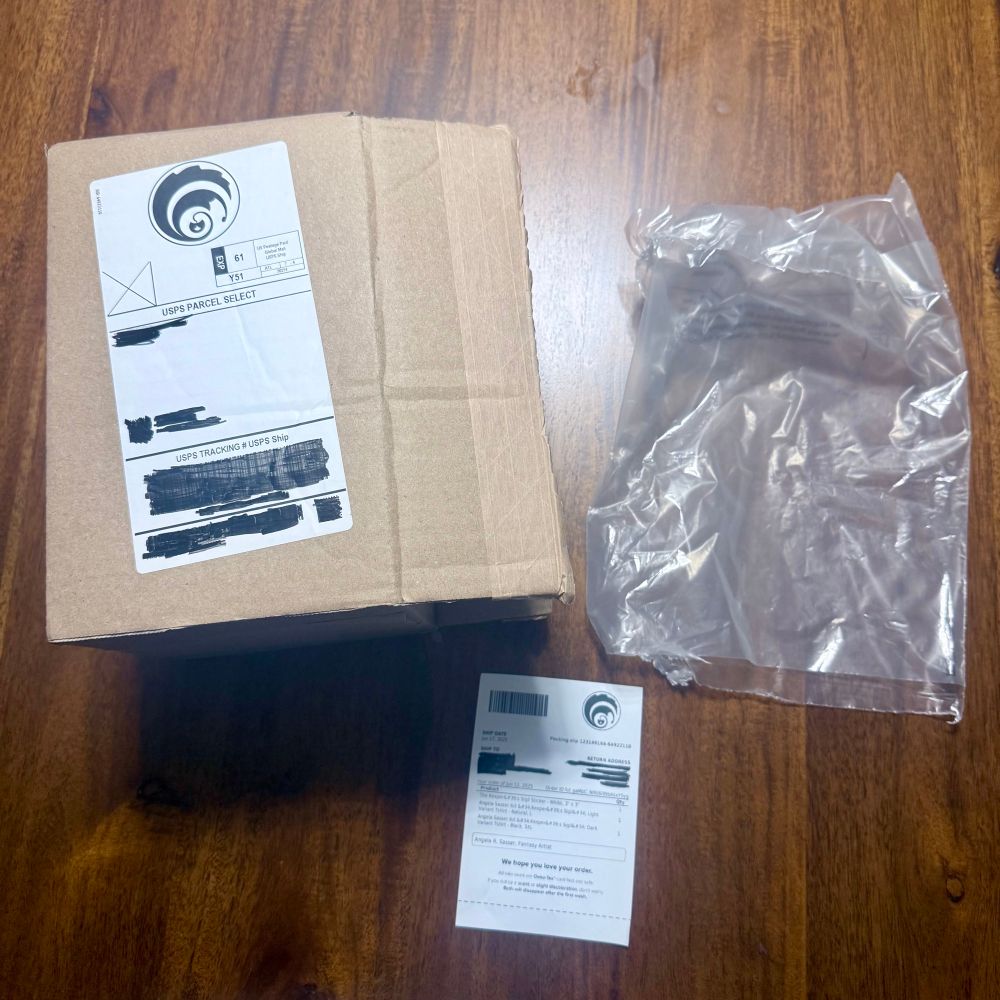 Branded packaging from Fourthwall. Tshirts are sent in bags, the sticker is bagged, and the desk mat is sent unwrapped.  A branded pack-in slip with your logo is included.