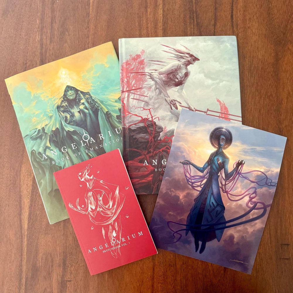 A collection of hardcover books, a sketchbook, and a print from Angelarium by Peter Mohrbacher and Eli Manaya.