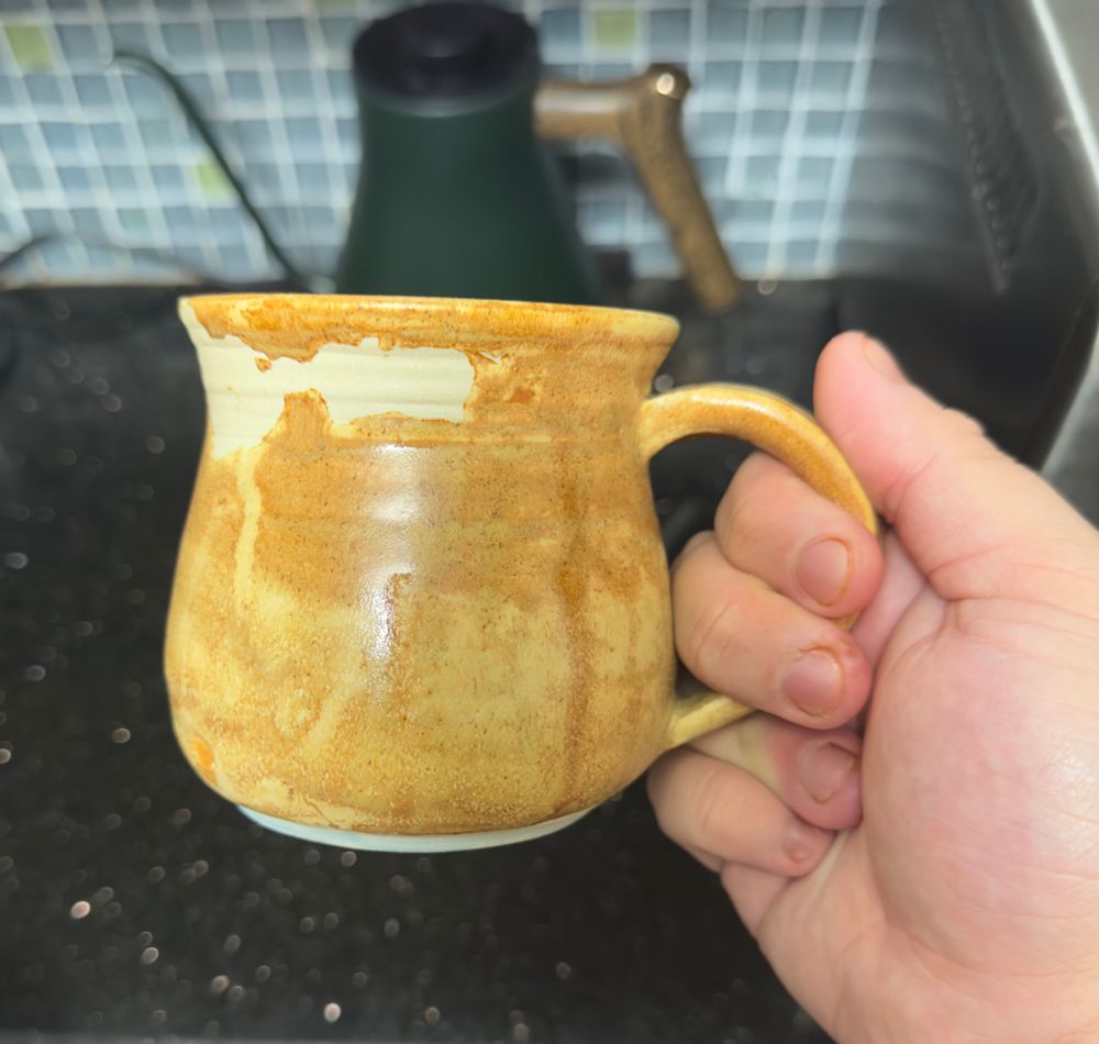 The other side of the same mug, revealing a much more dramatic surface with more speckling and running of pigment, as well as a large bare patch on the outside where glaze refused to stay.