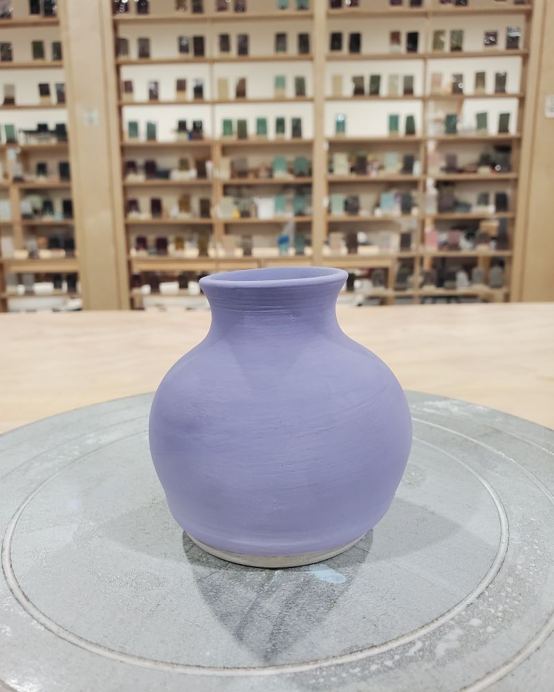 A small ceramic vase painted with purple underglaze.