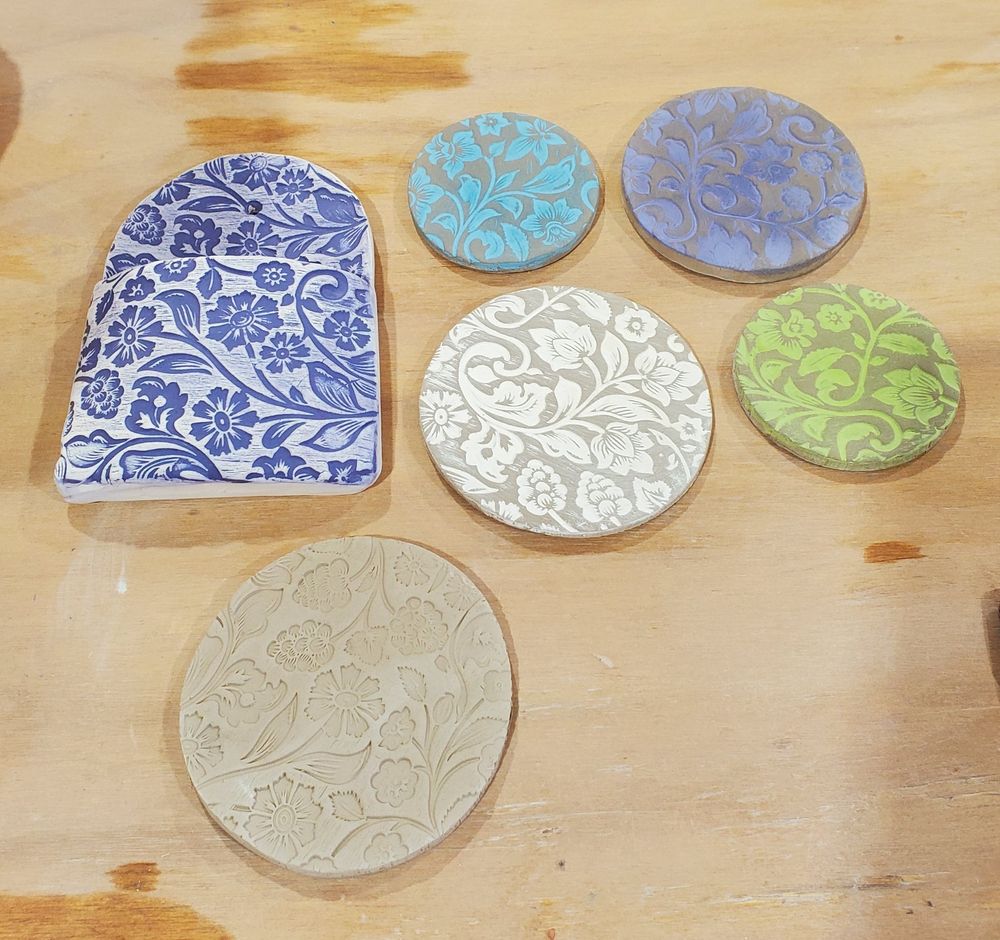 Pottery will floral imprint pattern. A wall vase and 5 circular coasters.