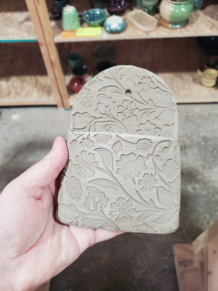 A wall vase with floral imprints.