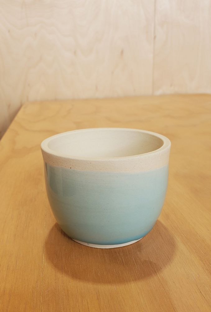 A small ceramic cup with pastel blue glaze