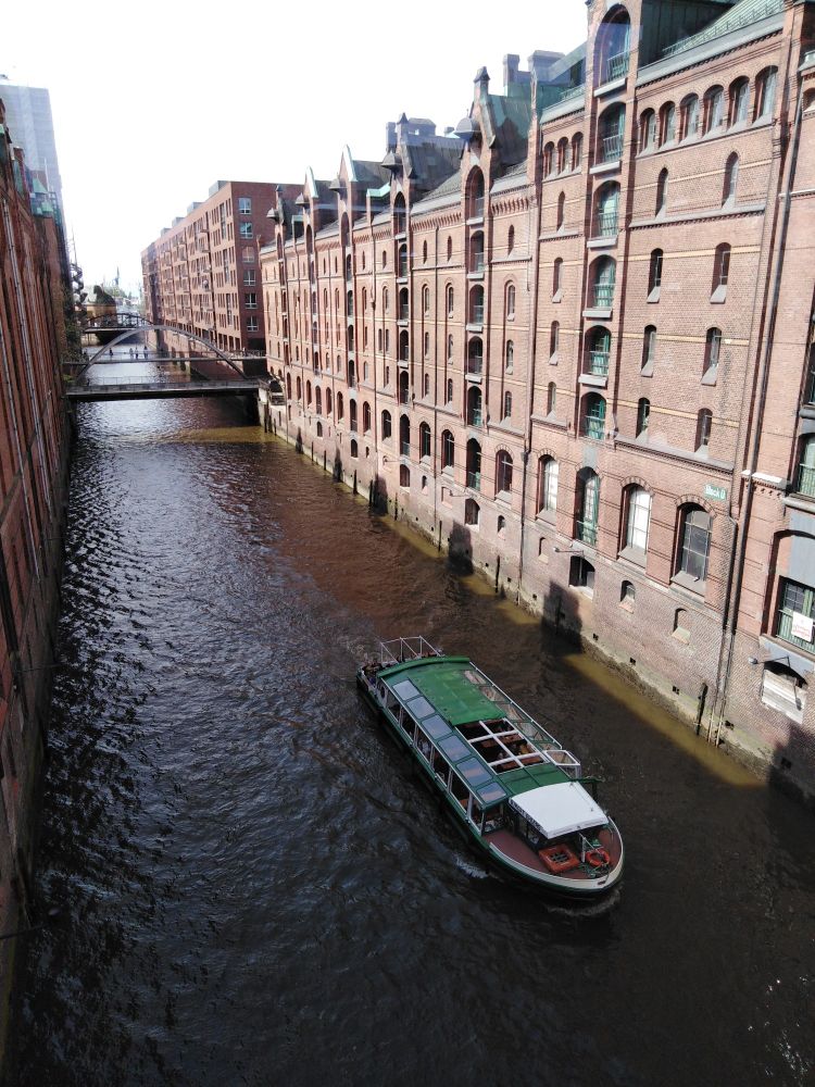 Aussicht vom Übergang im Miniatur-Wunderland (HH) in einen Fleet umrahmt von alten Gebäuden der Speicherstadt und einer vorbeifahrenden Barkasse.