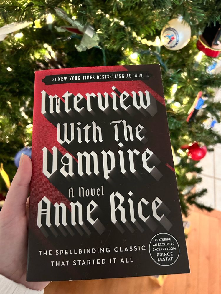 holding a copy of the interview with the vampire book by the xmas tree 