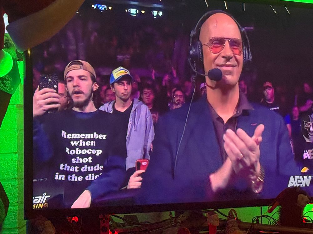 A guy wearing a shirt that says “Remember when Robocop shot that dude in the dick” onscreen on AEW Dynamite