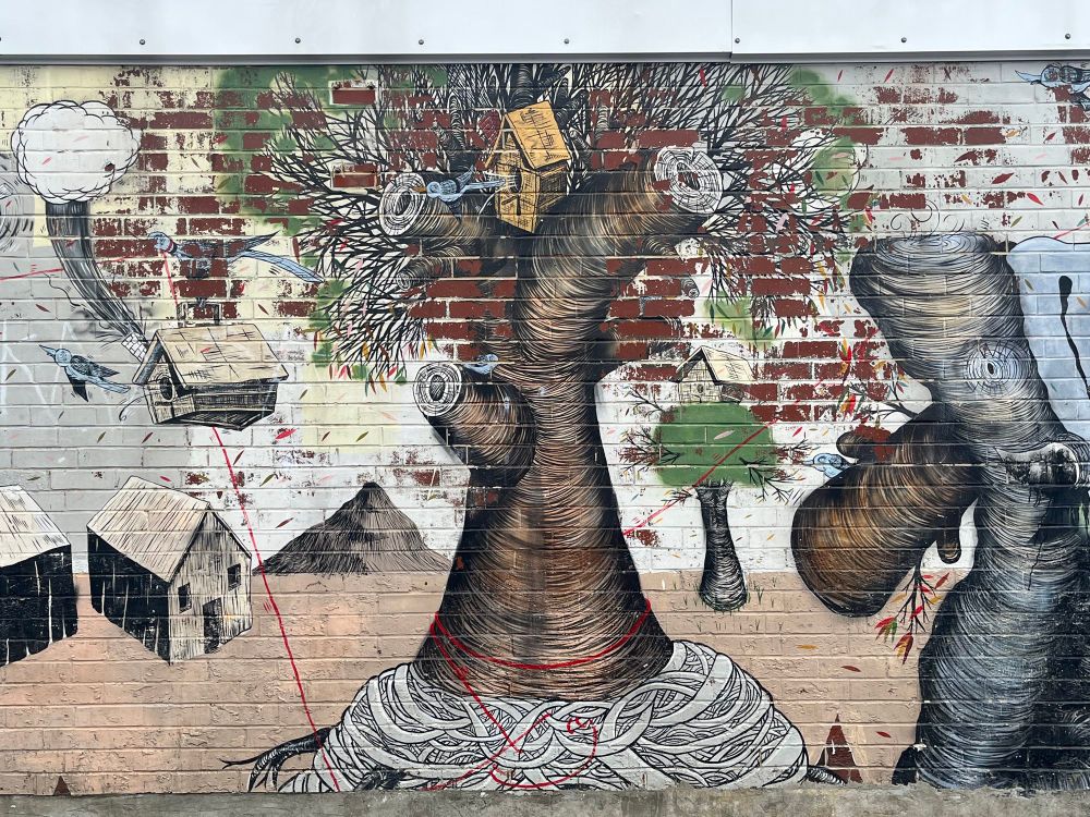 Brick wall with contoured tree, elephant body, bird houses, and barns