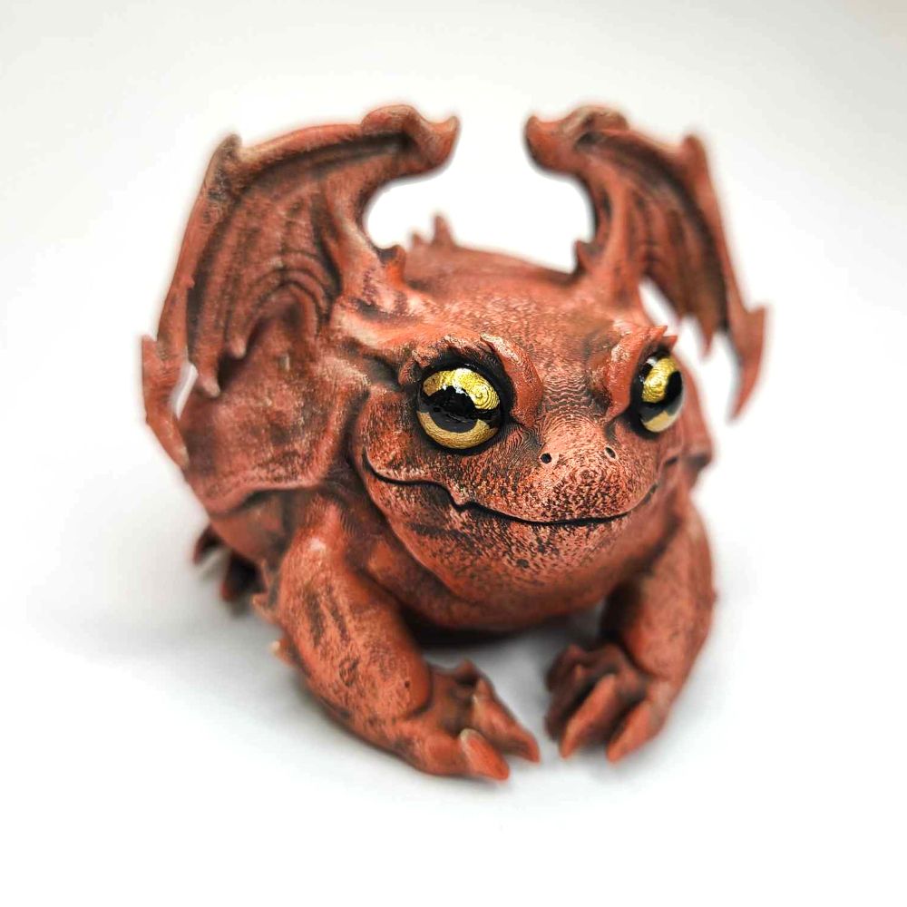 a tomato frog gargoyle sitting on a blank background