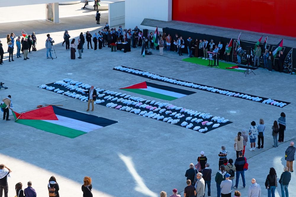 Place avec les drapeaux et des sacs blancs representant des enfants morts
