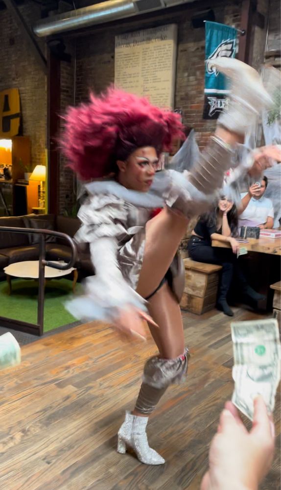 Drag queen in a yassified Pennywise the Clown outfit doing a high kick