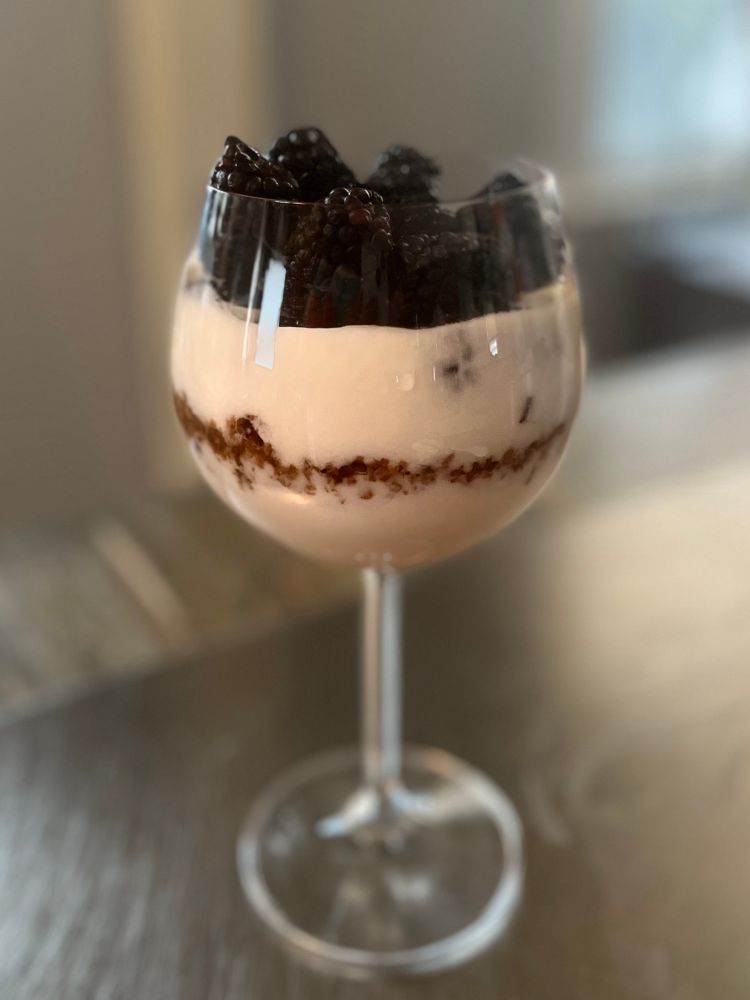 A parfait with layers of homemade yogurt, apple granola, summer jam and fresh blackberries.