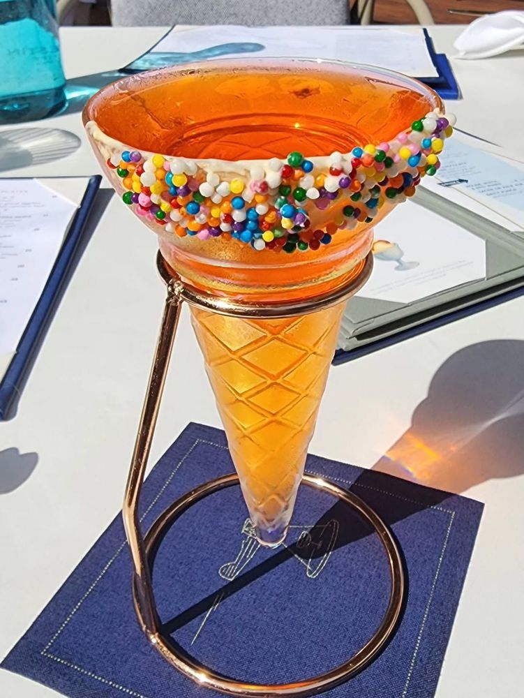 Drinking glass shaped like an ice cream cone. Due to it lacking any form of base it has to be held in a special metal holder.
