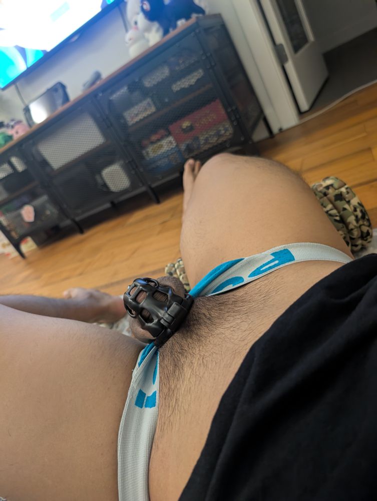 Me laying on the floor, foam rolling one leg with my jockstrap pulled down showing my cage