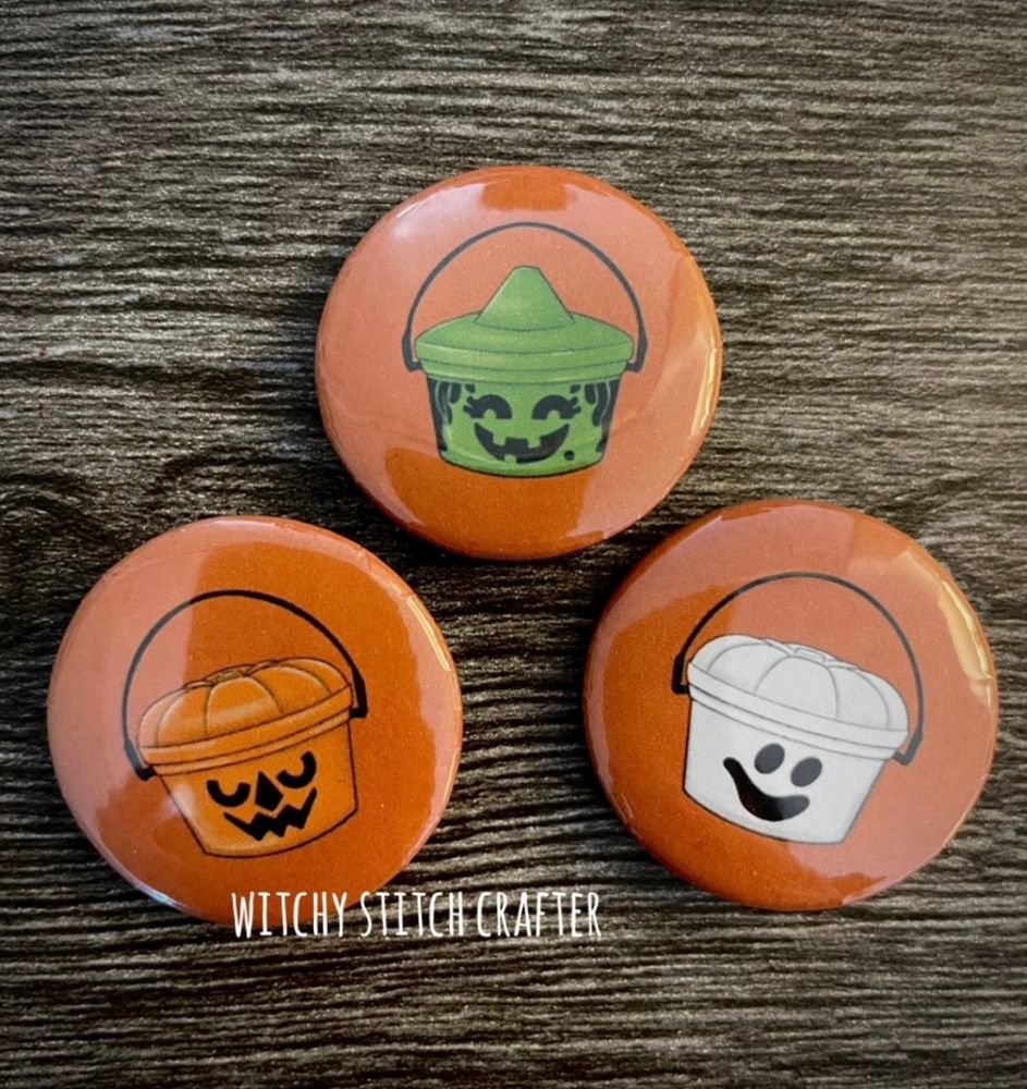 Photo - button badges featuring iconic nostalgic Halloween candy treat pails in designs like a Jack o Lantern, Witch and Ghost 