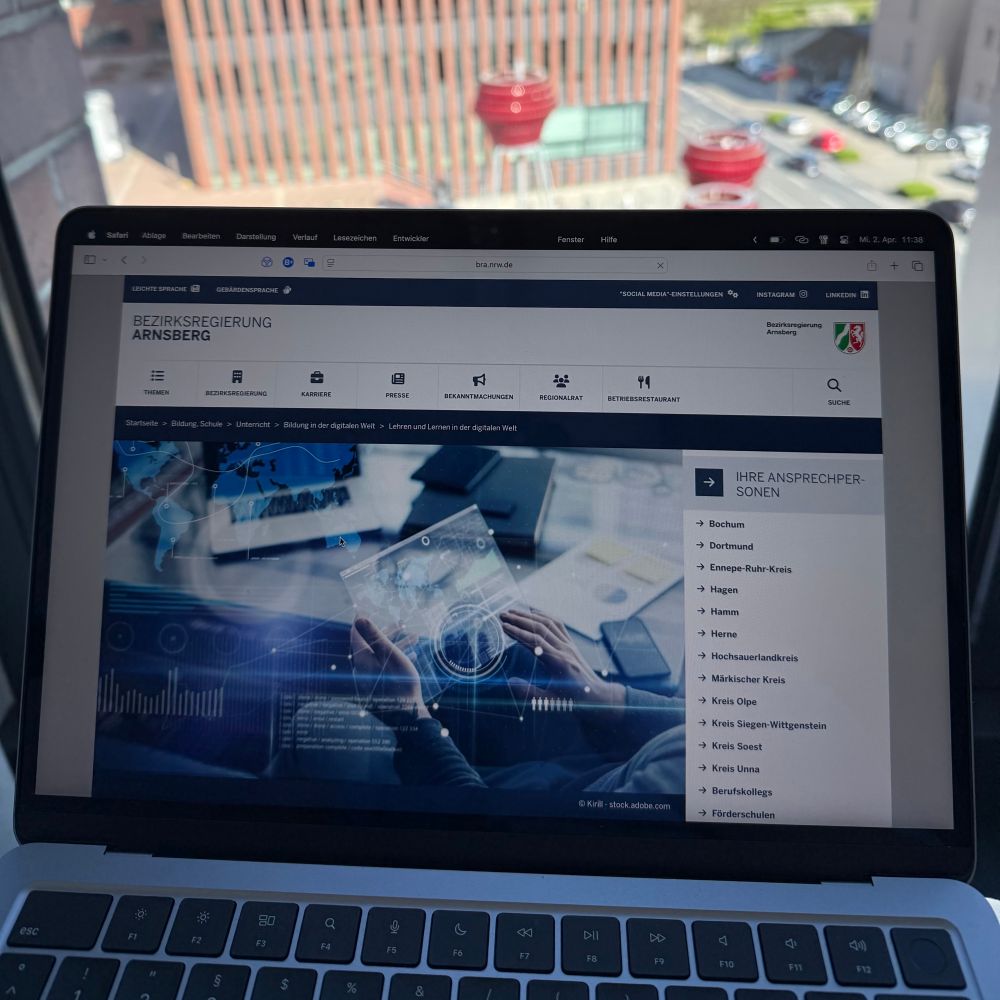 Foto von Laptop mit Internetseite der Bez.-Reg. Arnsberg, Vorplatz vom Dortmunder U im Hintergrund