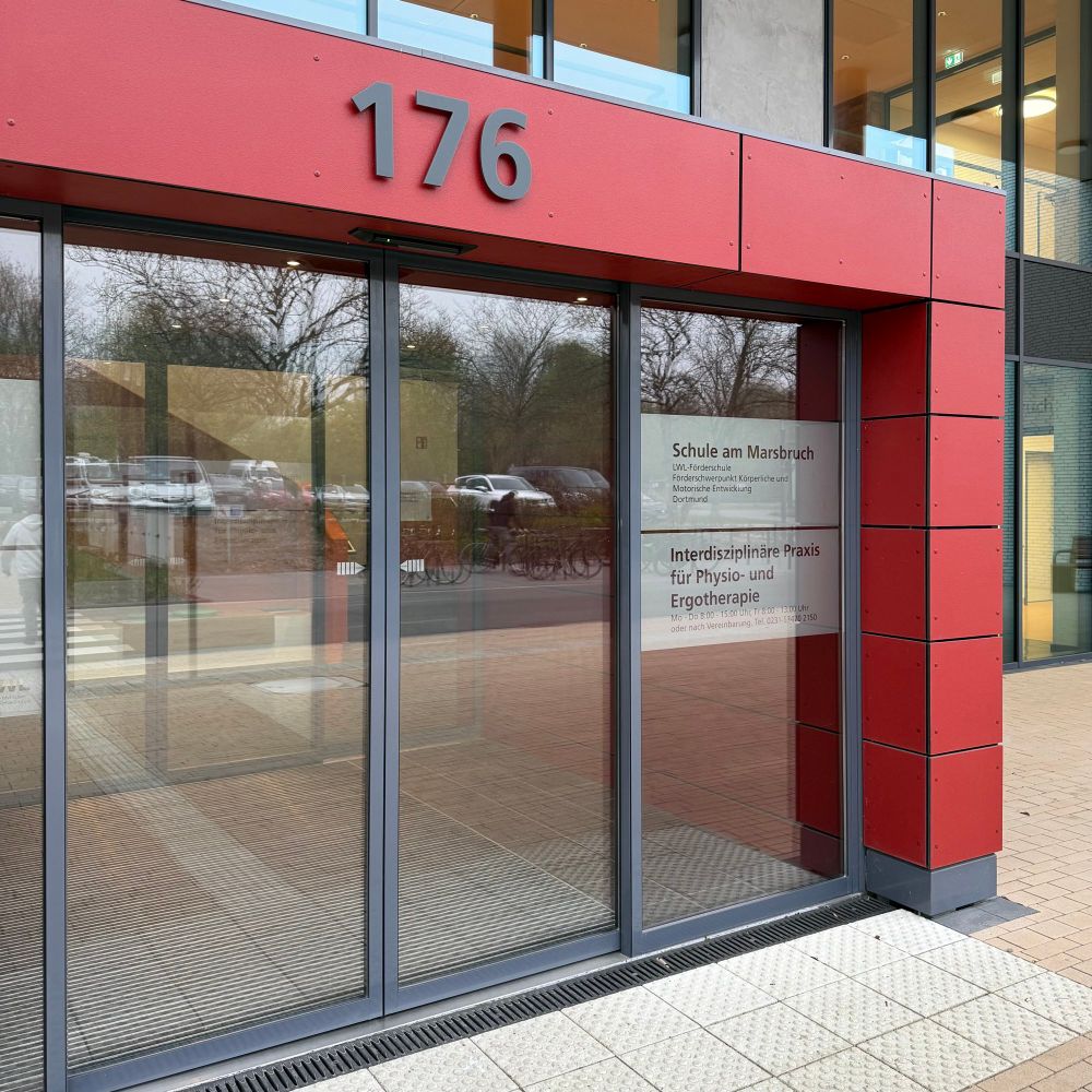Haupteingang der Schule am Marsbruch mit rotem Vordach und schwarzer Hausnummer 176