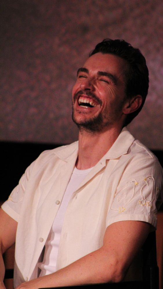 Dave Franco with his head thrown back in laughter