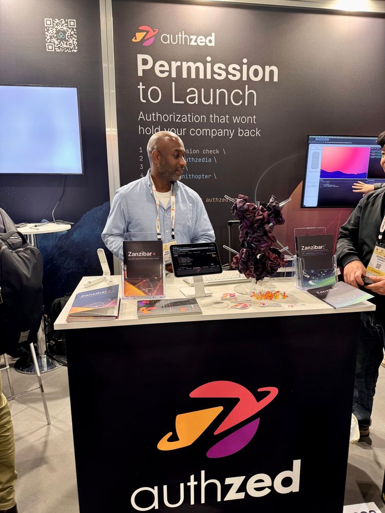 Kelsey Hightower at the AuthZed booth signing a copy of the Zanzibar annotated edition containing his forward.