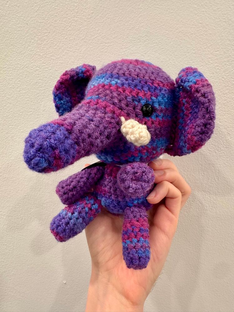 A knit elephant with yarn made of blues, purples, and pinks.