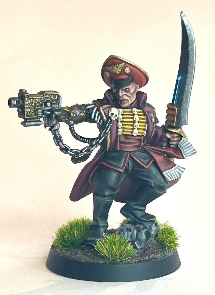 Wh40k Commissar Prefect (I think). 
With a metal arm, cummerbund, bolt pistol and power sword. Also possibly frogging.