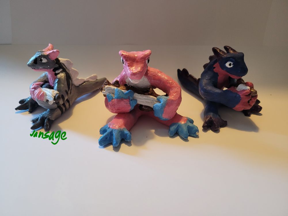 Left: a Guitarist dragons with the colors of the demigirl flag.
Right:  a lyre-playing dragon with the colors of the bi flag.
Middle: a Guitarist Dragon with the colors of the trans flag 