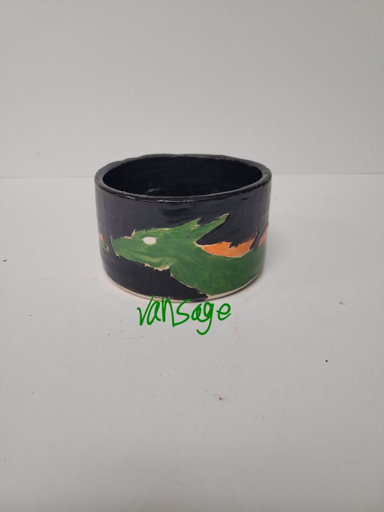 Small, black, ceramic cylinder with a green dragon on it. 