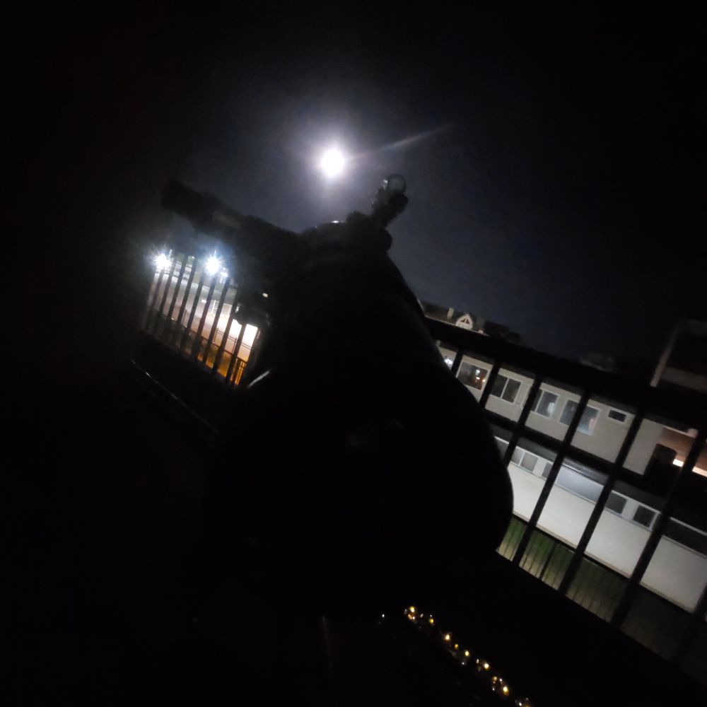 Photo of a telescope behind the moon.