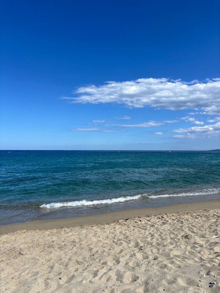 La plage, le ciel est bleu avec quelques nuages blancs