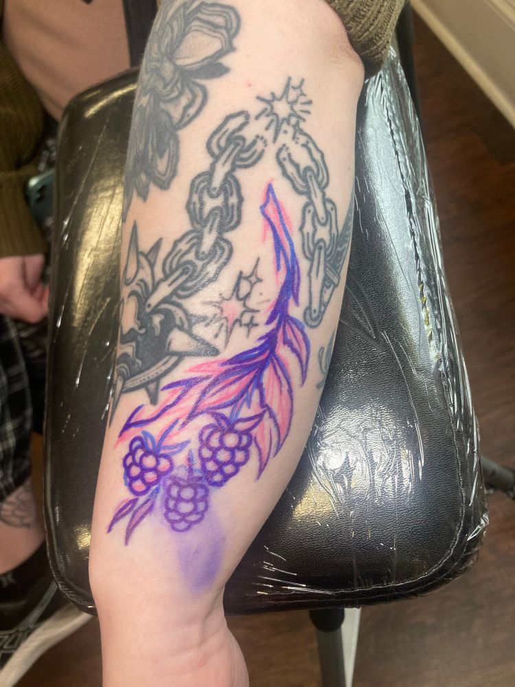 Drawn-on tattoo concept of blackberries using markers on the side of a wrist, then tattooed over