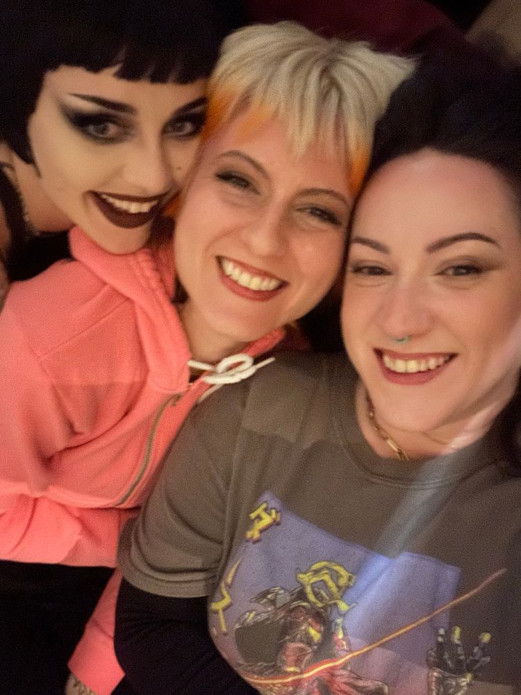 Selfie of me and my two friends. We’re laying on a bed, smiling up at the camera