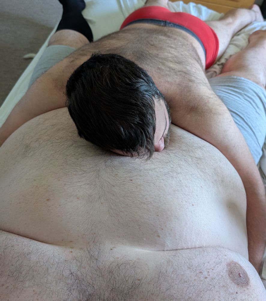 Small chaser man resting comfortably on his big mattress boyfriend's belly