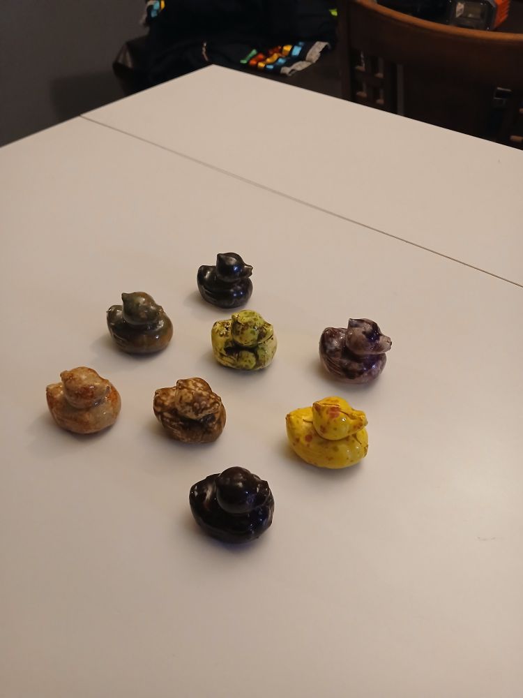 A collection of eight (8) ceramic rubber ducks. Each duck is sporting different glazes.