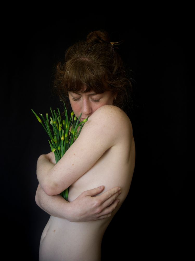 Liv holding garlic scapes, in a spiral pose.