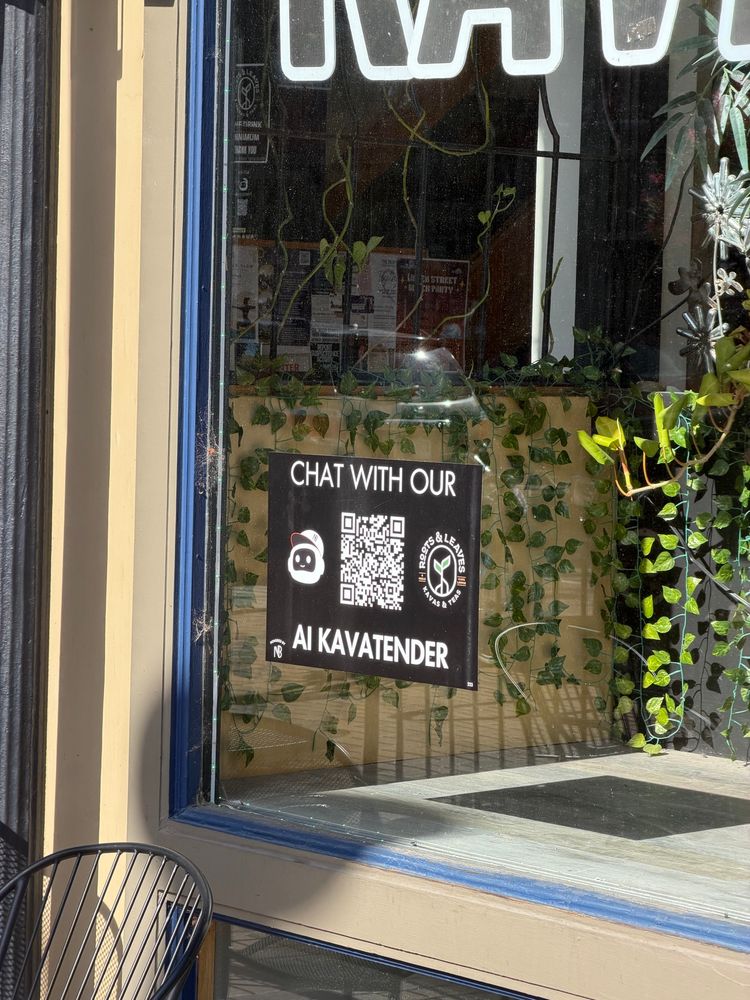 A sign in a shop window that says “chat with our AI kavatender”