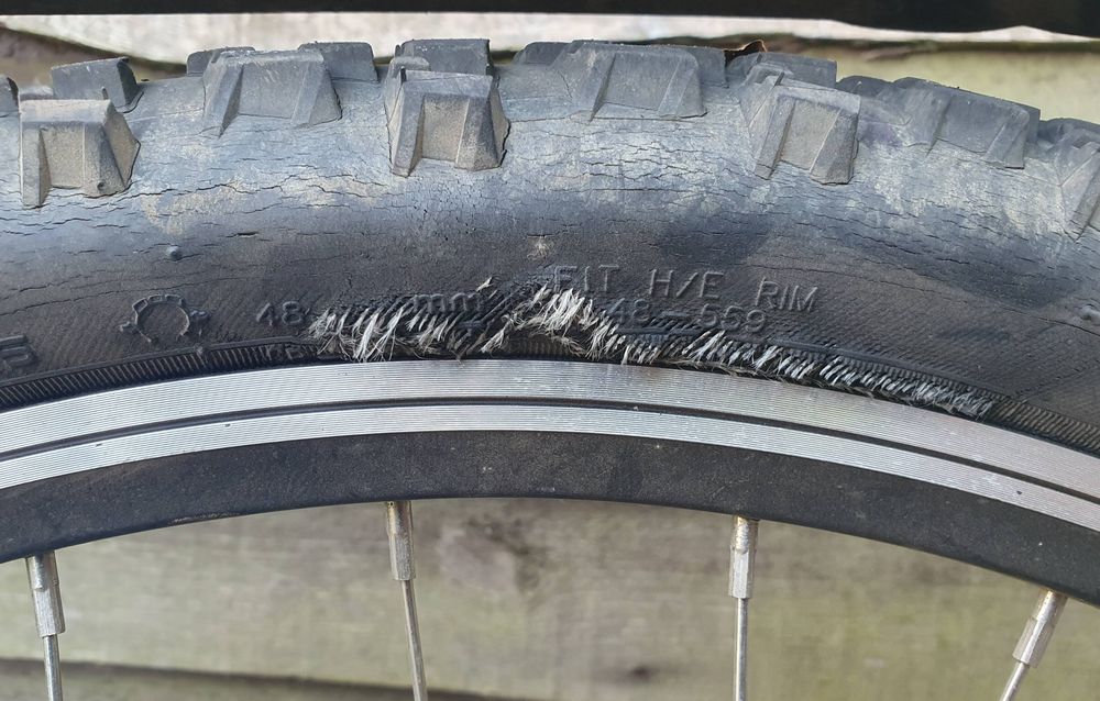 A bike tyre, starting to split down the side, white fibres poking out.