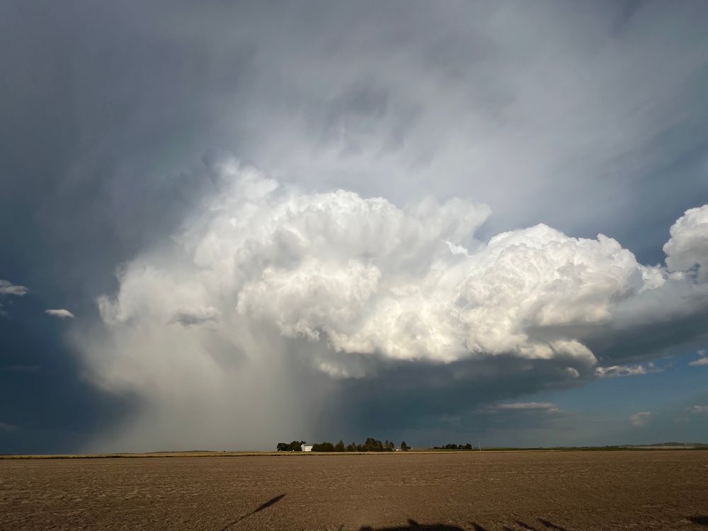 Cumulonimbus cloud with a white waterfall of hail spilling out the left side.