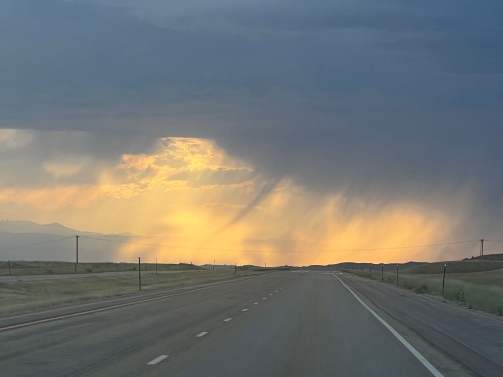 A backlit rain shaft with a tapered dark tendril in the middle
