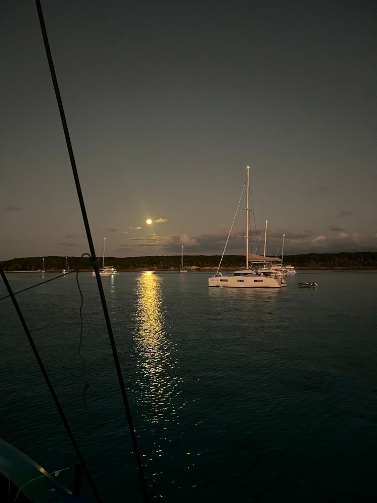Full moon over a bay with sailboats.