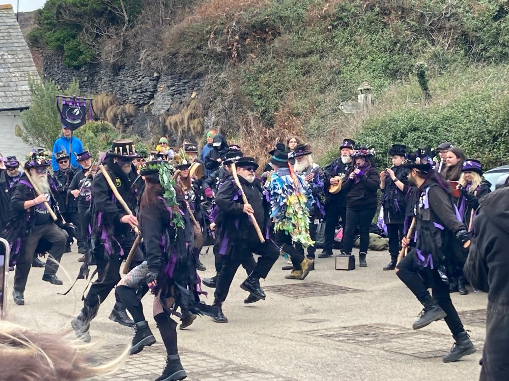 Morris dancers in black and purple, dancing in a car park.