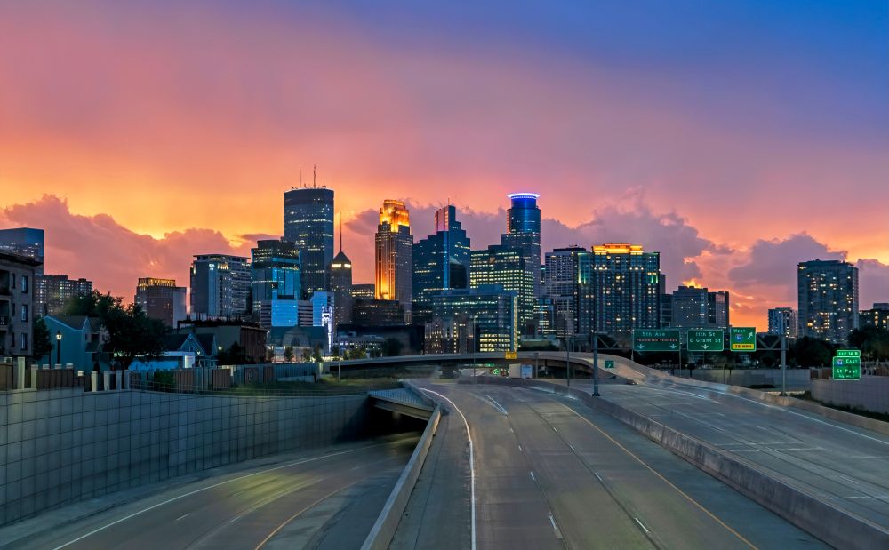 Three skyline of Minneapolis with stormy clouds lit up by a sunset