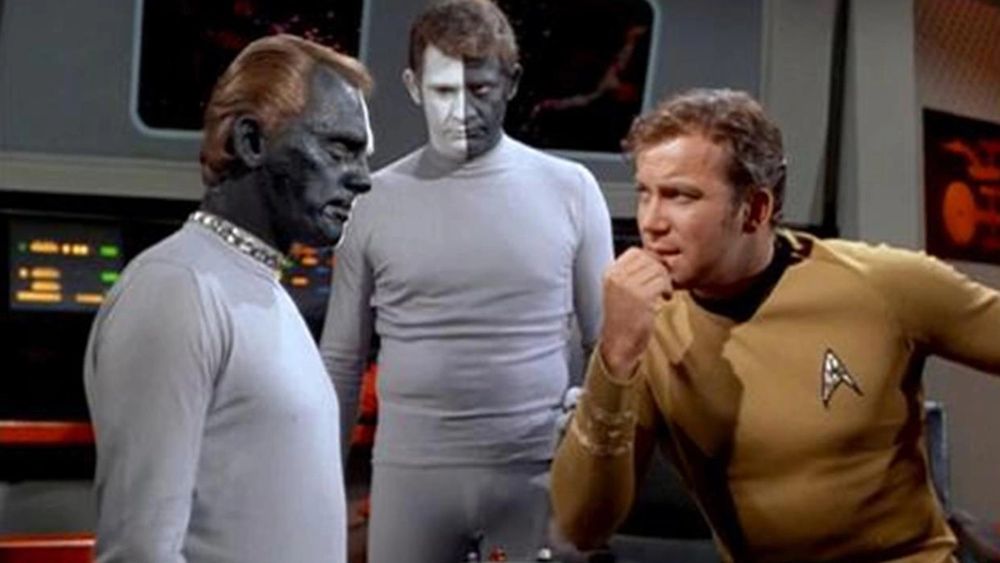 A scene from the original Star Trek series where men are painted black on one side and white on the other