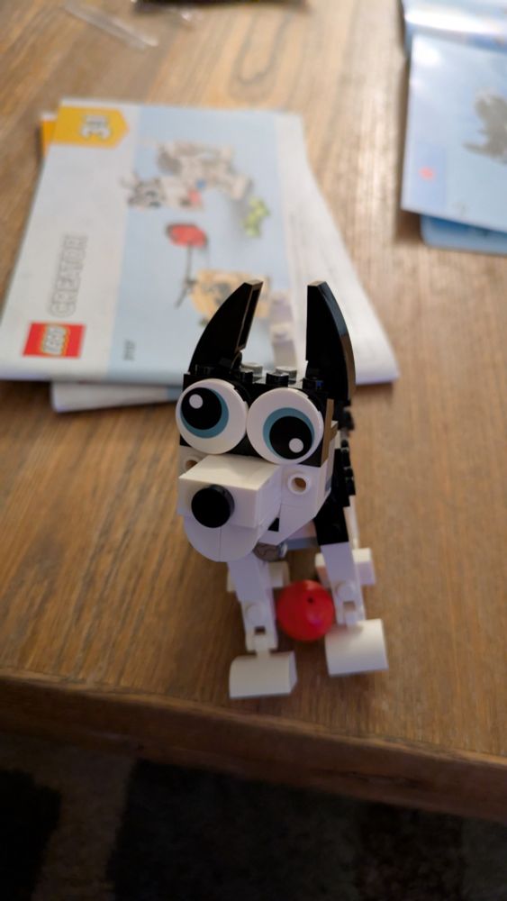 A Lego husky sitting with its ball on a table