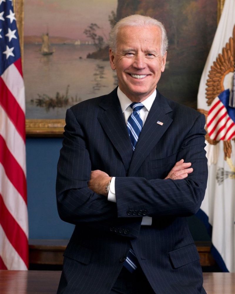 Picture of smiling Joe Biden standing with his arms crossed.