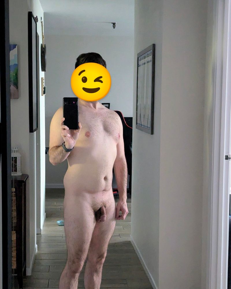 Nude selfie focusing on the chest area with the winking face emjie covering the subjects face. 